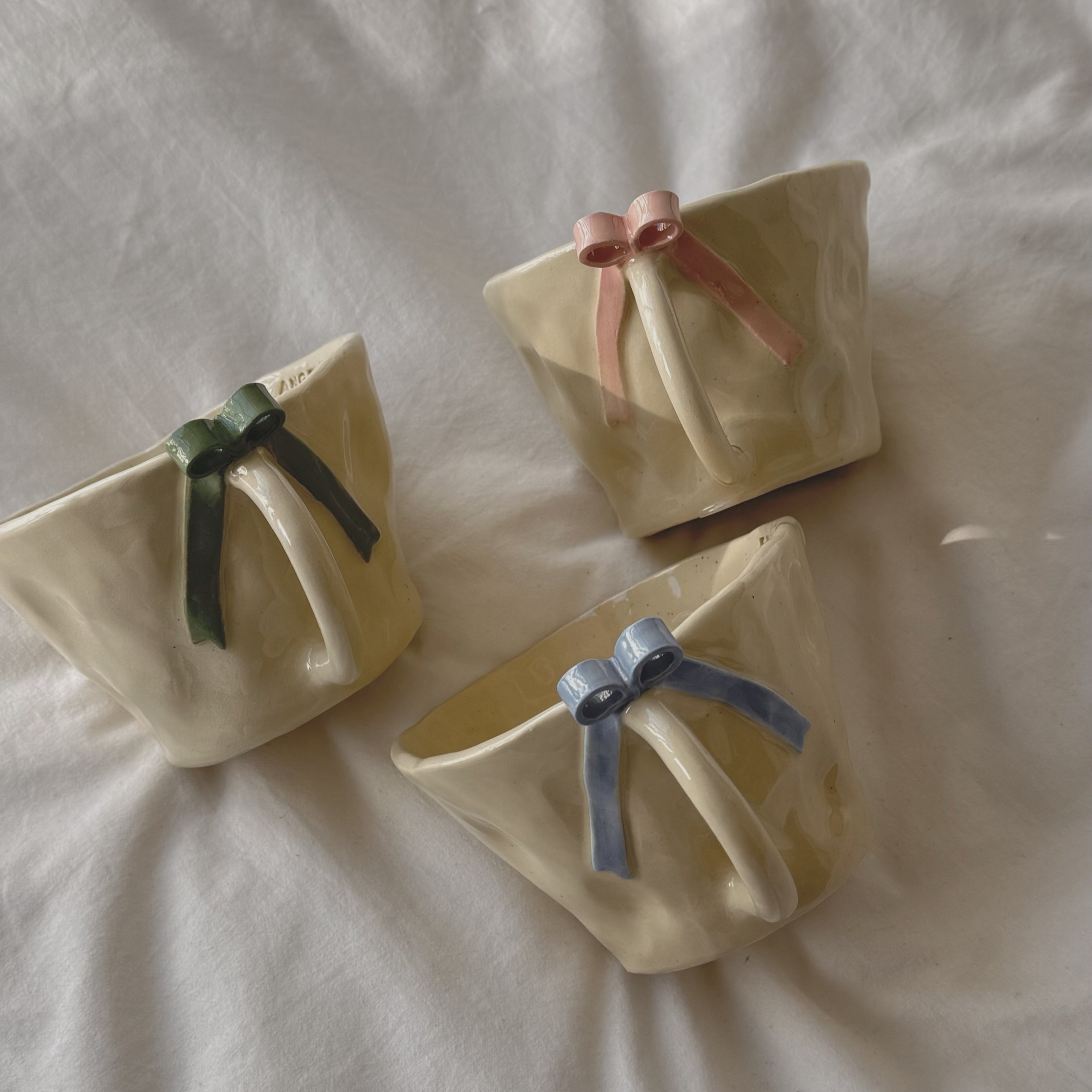 Blue, Green, and pink ceramic bow mugs from Beleza Curated section.