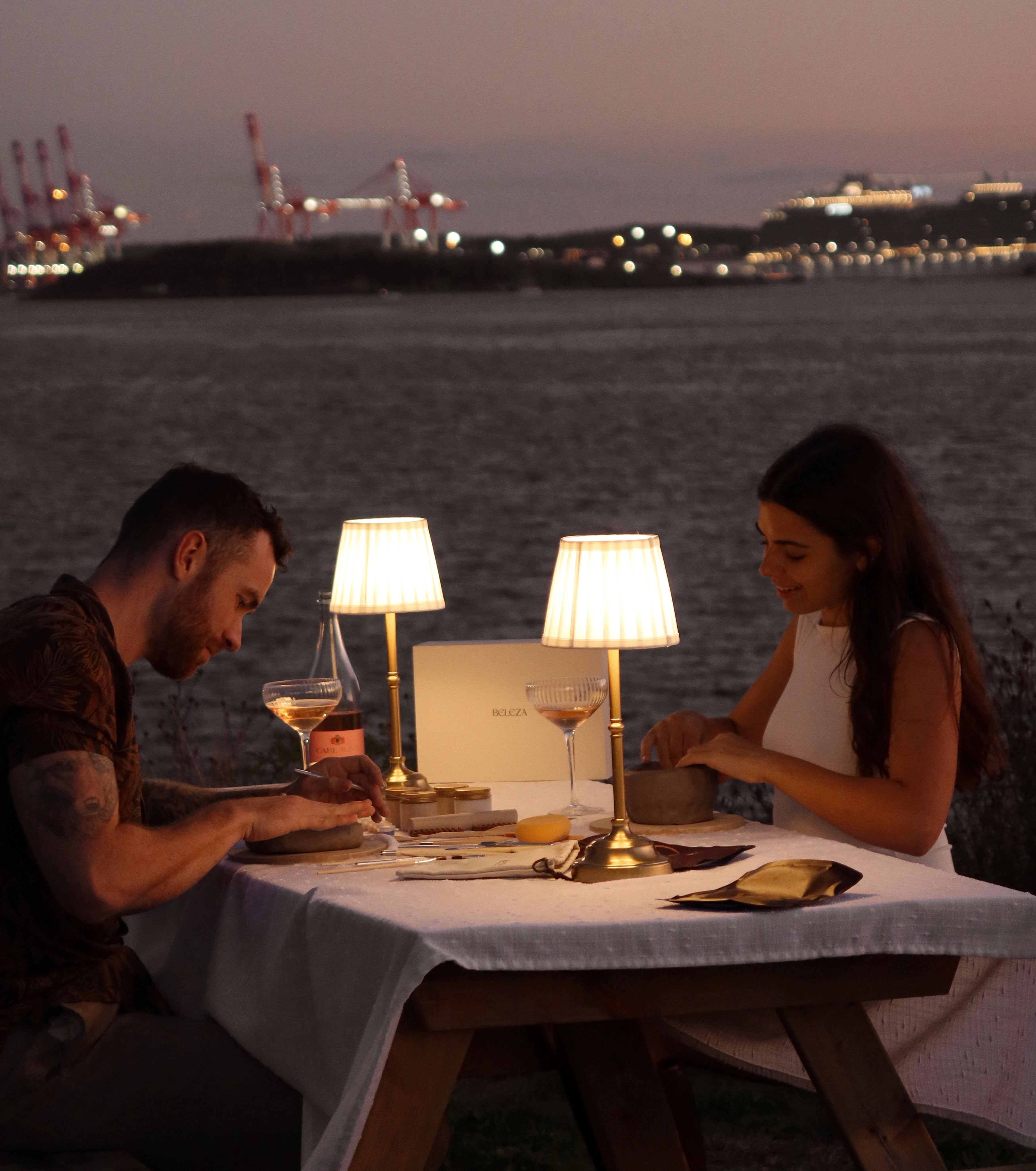 Couple (Beleza founders Josh & Calista) doing pottery by the sea at night with romantic pottery table setup.